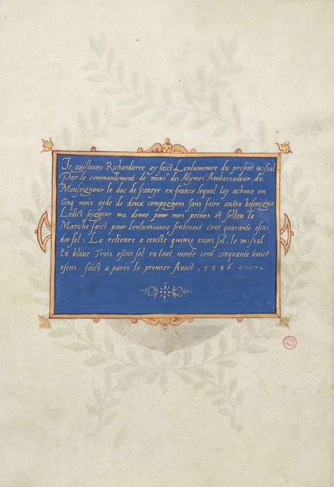Page of a book. This white page of a book features a blue rectangle containing a passage of ornate gold text. It is surrounded by a decorated golden frame. Around the frame, a subtle, pale grey pattern featuring leaves can just be seen.