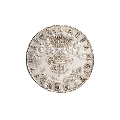 Colour photograph. This photograph documents a round, silver coin against a stark white background. Embossed text encircles the coin, and in the centre three ornate crowns are stacked on over the other.